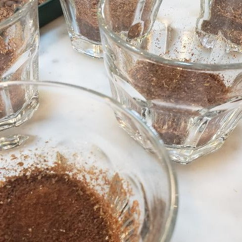 ground coffee in glass cups on a white tabletop.