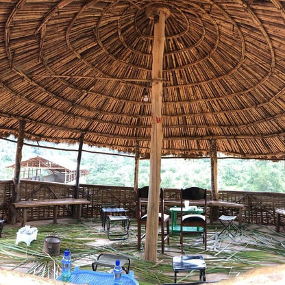 traditional Ethiopian straw dwelling with circular roof pattern.  Chairs are arranged for an Ethiopian Coffee Ceremony, the traditional way of preparing the coffee beverage in Ethiopia.  During this ceremony green coffee is roasted on a pan, before being ground and brewed.  Often incense is burned, and coffee is served with popcorn.