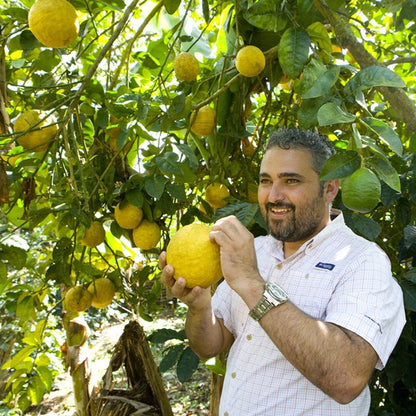Omar Rodriguez holding an indigenous Honduran citrus fruit similar in size to a pomelo.  Omar is the leader of the COCAFCAL coffee cooperative in Copan Honduras, also known as Capucas